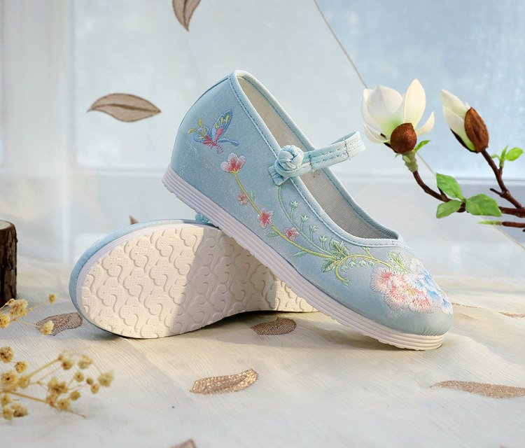Blue embroidered shoes laid on linen background