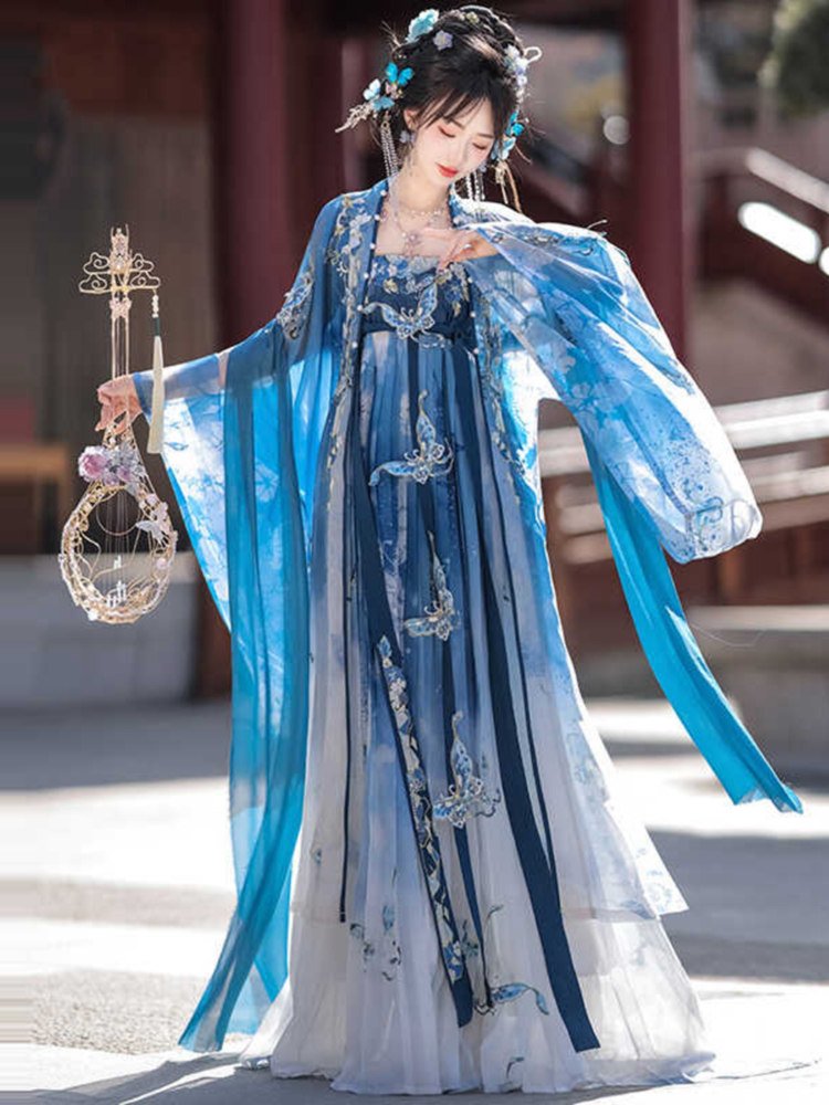 Model posing in blue fairy Hanfu dress with embroidered butterflies and gradient chiffon layers.