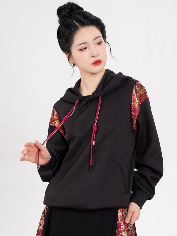 Black hoodie featuring red traditional cord and brocade panel accents