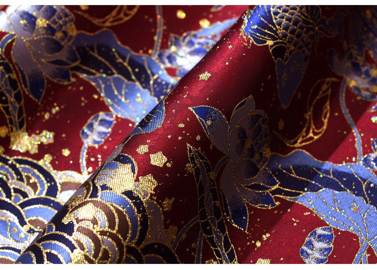 Close-up of shimmering red-blue fabric blend with gold embroidery