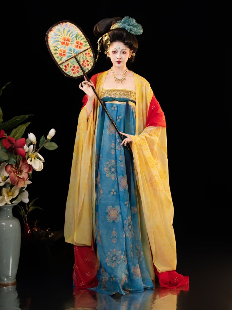 Model holding a traditional Chinese fan while wearing a Dunhuang-inspired hanfu dress.