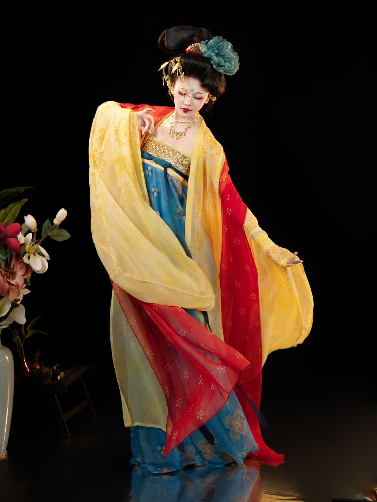 Model displaying the yellow and red layered wide sleeves of a Dunhuang-style hanfu dress.