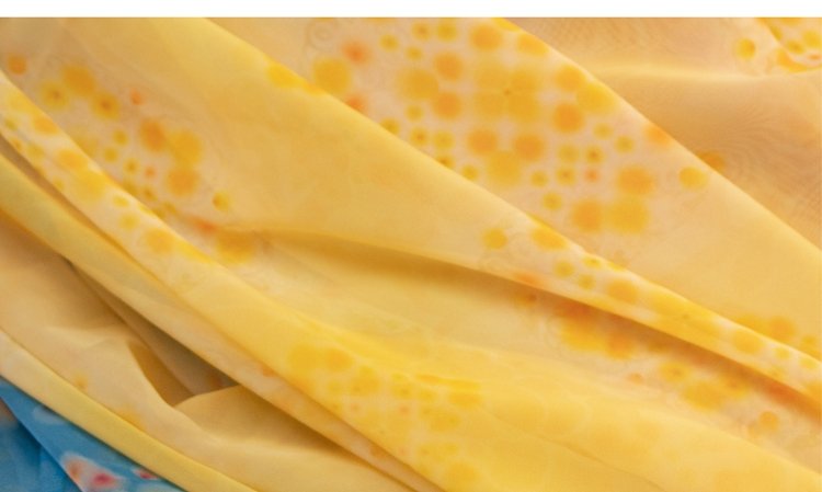 Close-up detail of yellow chiffon fabric with soft floral patterns.