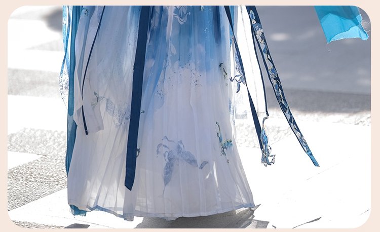Model wearing blue butterfly embroidered Hanfu outdoors with sunlight on chiffon fabric.