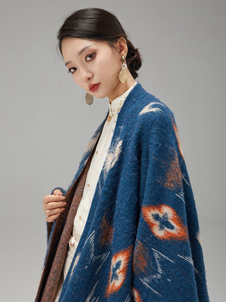 Close view of the model wearing a blue ikat-pattern shawl over a cream blouse.