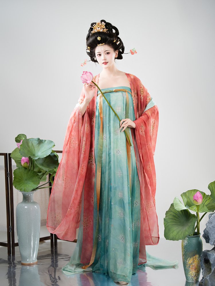 Model wearing peach-red and mint-green Tang style Hanfu dress with flowing chiffon shawl, standing in traditional setting.