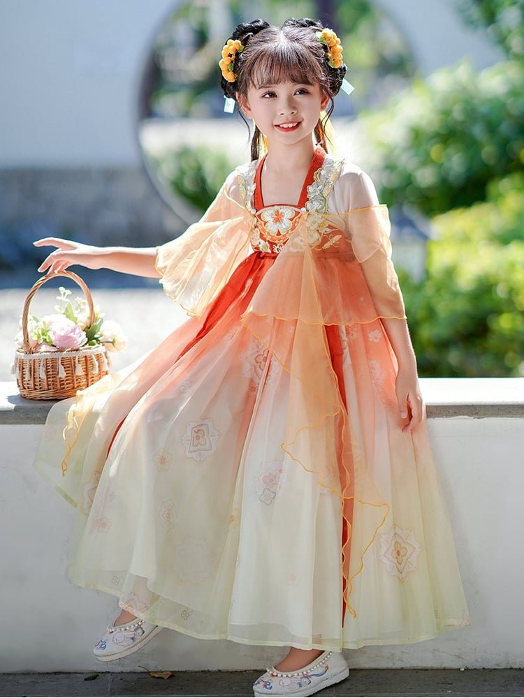 A girl wearing an orange Chinese princess dress standing outdoors with a basket