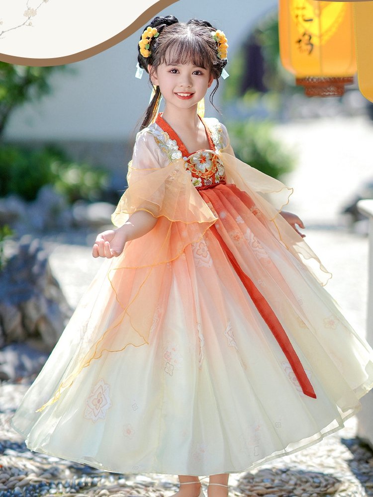 Girl twirling in a layered orange and ivory Chinese dress outdoors