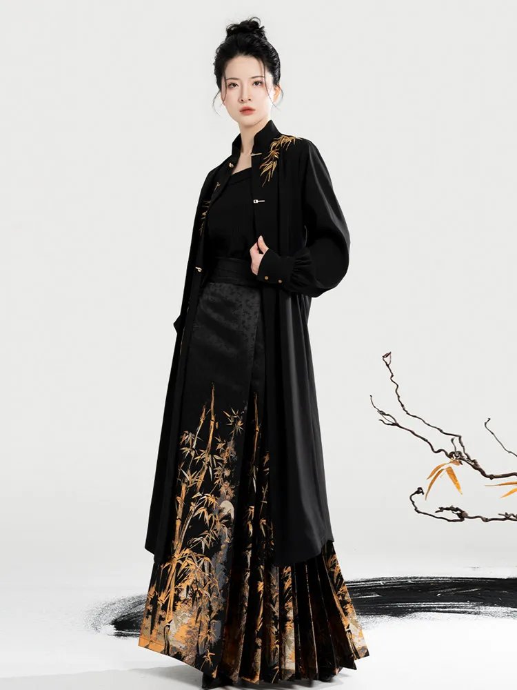 Model wearing black Ming-style coat and golden bamboo brocade mamian skirt, full-body front view.