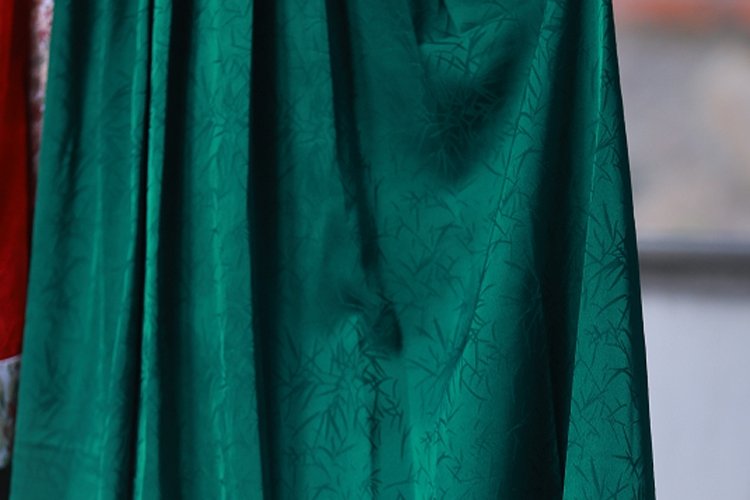 Close-up of pleated green Hanfu skirt fabric showing elegant folds