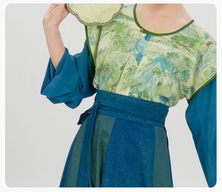 Detail of round-collar blouse with printed floral pattern in green and yellow tones