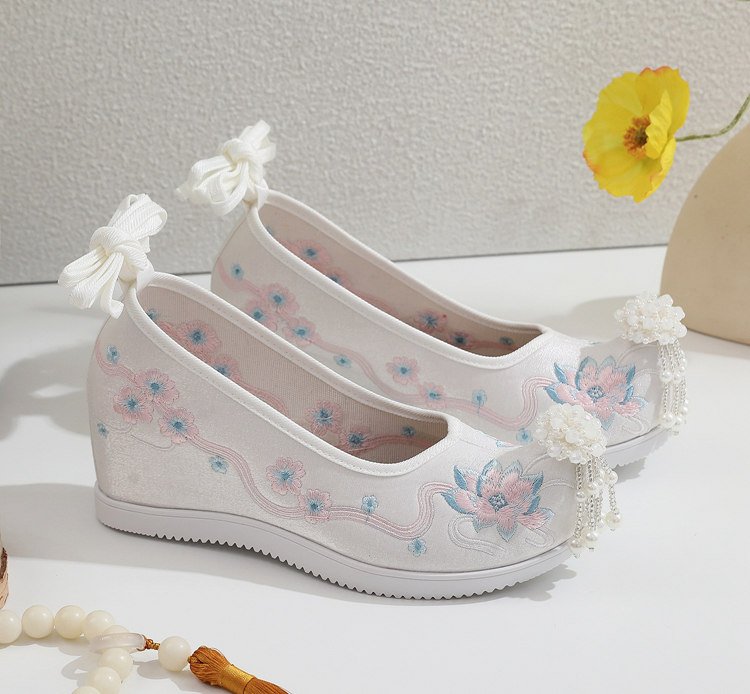 Embroidered Hanfu shoes placed on wooden background