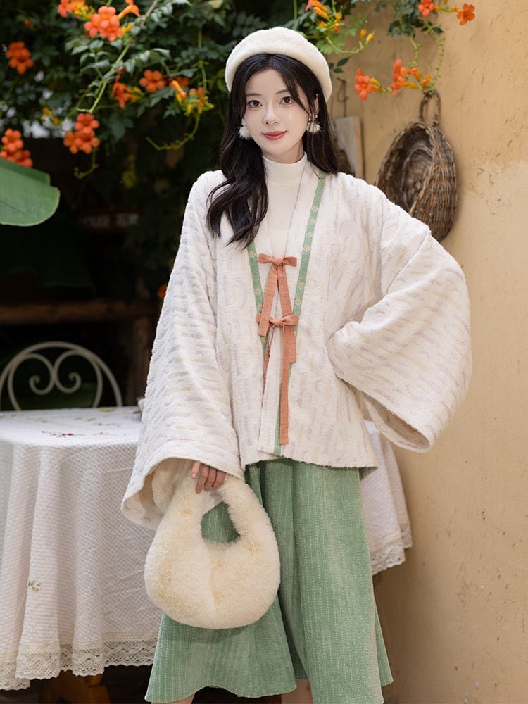 Model wearing cream and green Hanfu in sunlight near table.