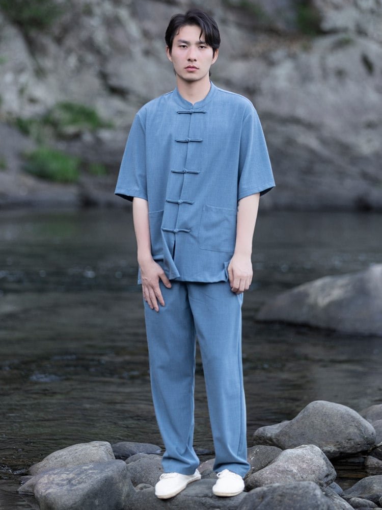 Model wearing a blue men’s Chinese summer outfit with a short sleeve mandarin collar shirt and matching pants, full body front view.