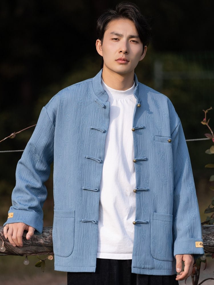 Model in a light blue Chinese Tang-style jacket with frog buttons, shown in a casual outdoor pose.