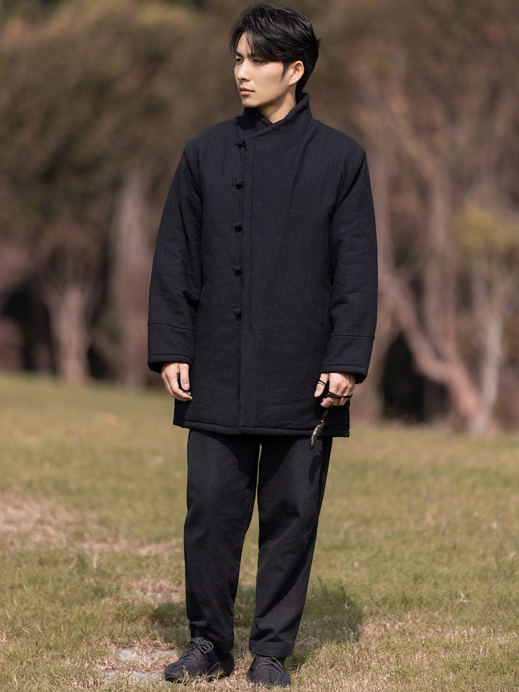 Full-body outdoor view of a man wearing a black padded Chinese winter Tang jacket.