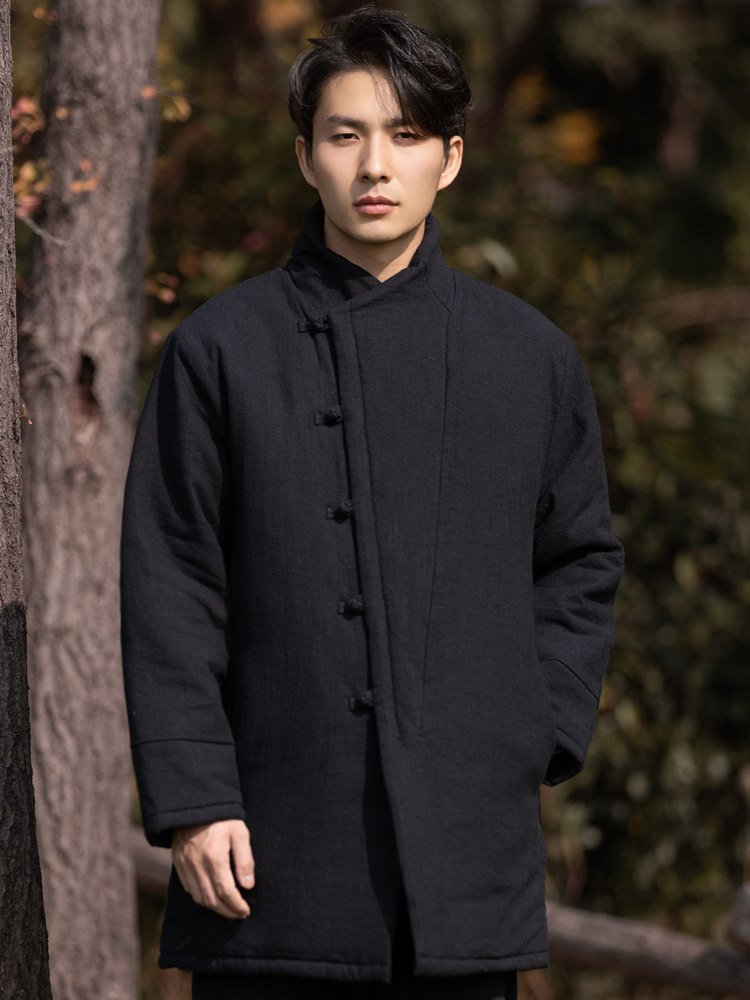 Side view of a man wearing a black padded Chinese winter Tang jacket with frog buttons.