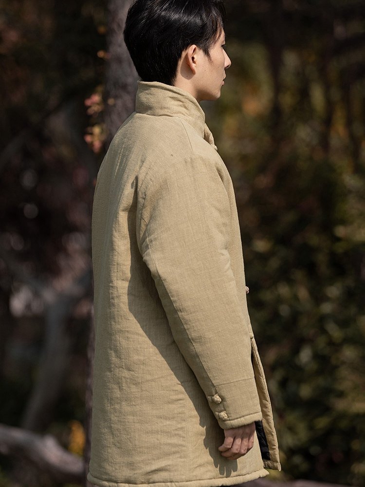 Side view of a man wearing a yellow padded Chinese winter Tang jacket with a mandarin collar.