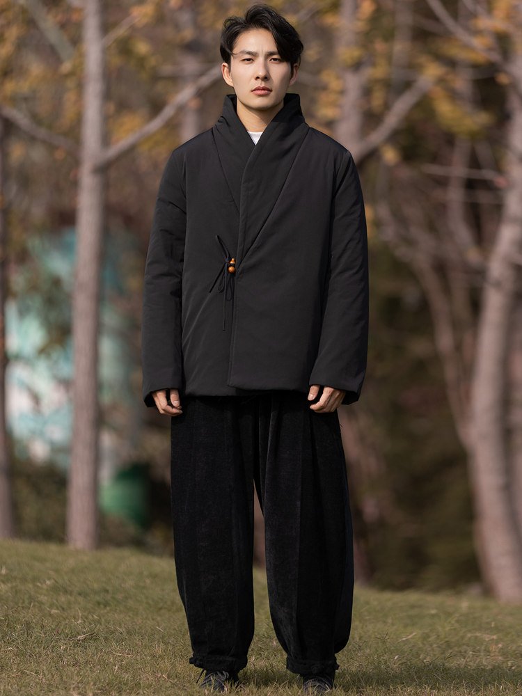 Full-body front view of a man wearing a black Chinese wrap winter jacket with padded design.