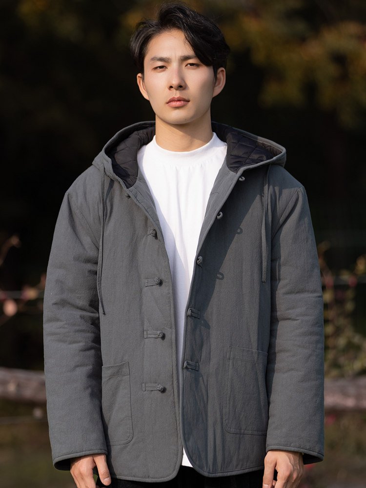 Full-body front view of a man wearing a gray hooded Chinese winter jacket with frog buttons and thick padding.