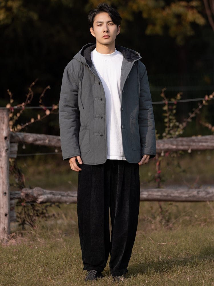 Full-body outdoor view of a gray hooded Chinese winter jacket with padded design and frog-button closure.