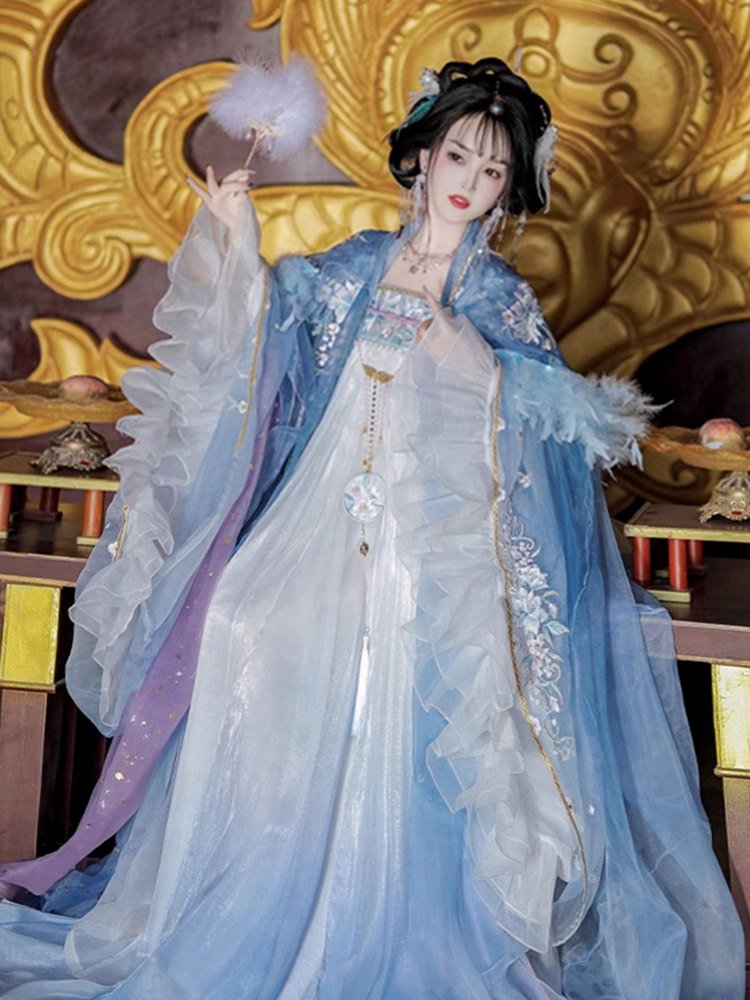 Model sitting in blue Hanfu with layered feather cape