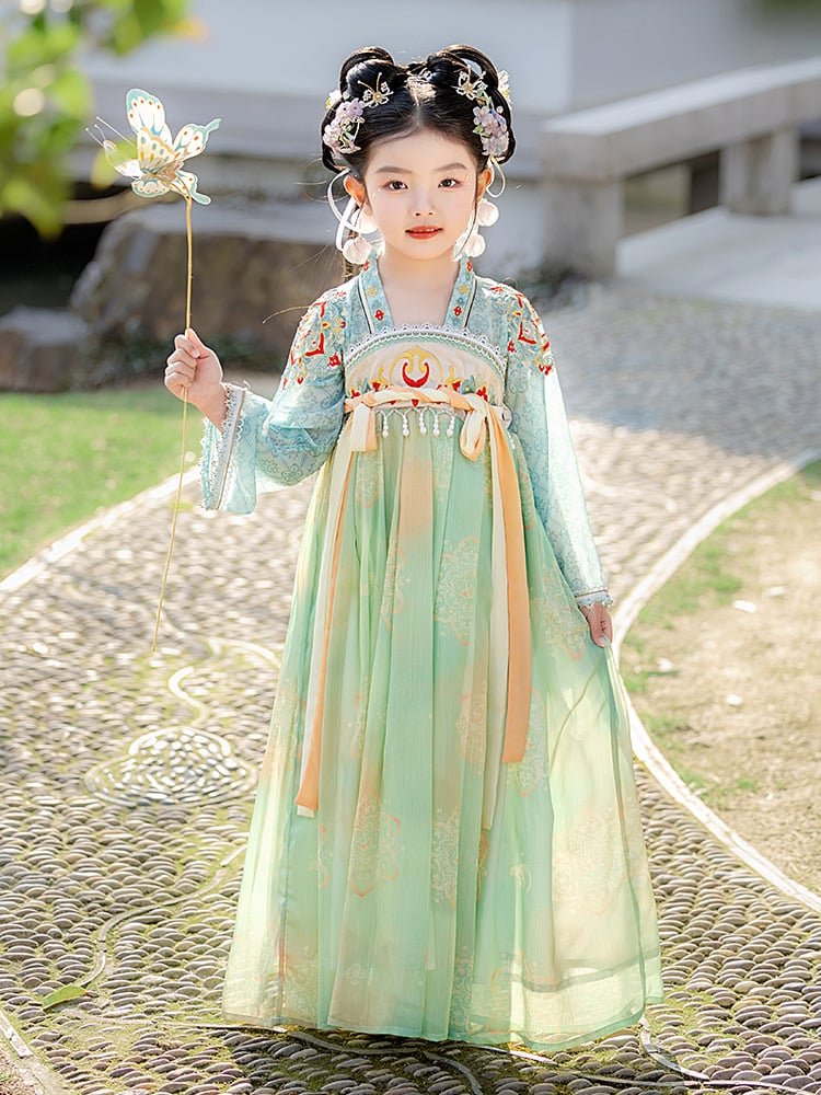 A girl wearing a green Tang dynasty dress holding a butterfly fan outdoors