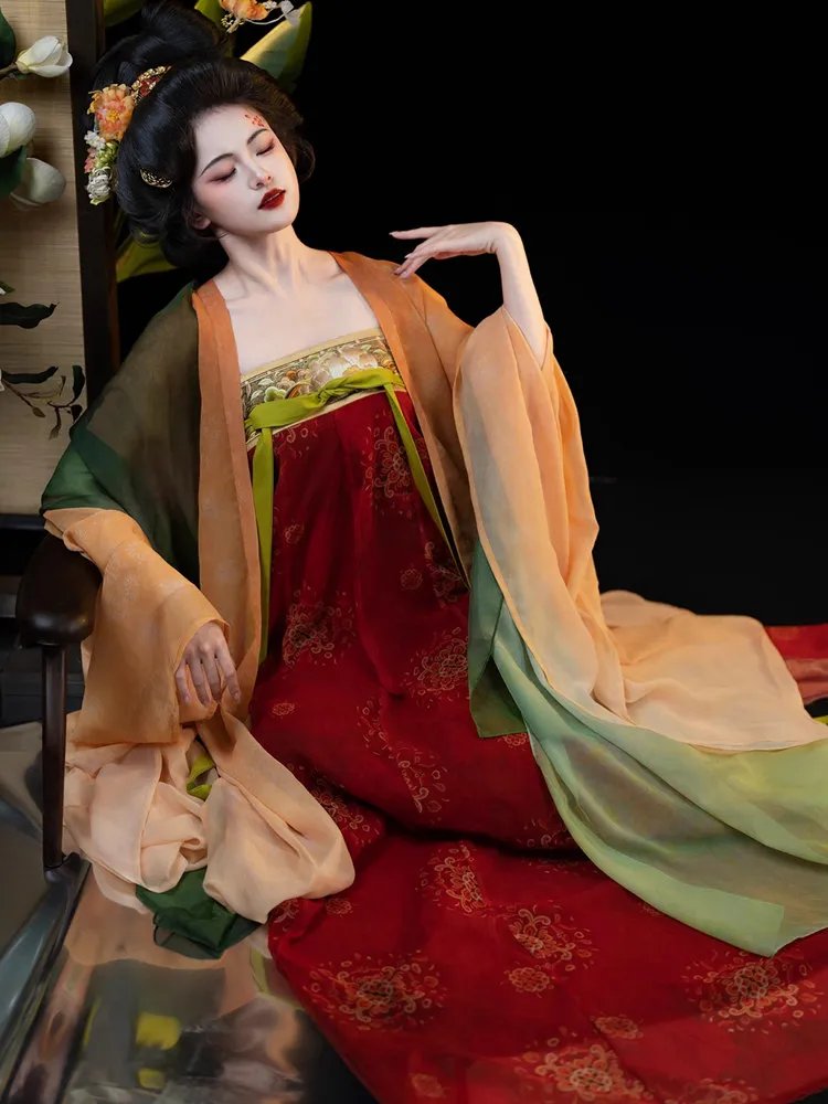 Model wearing red-green Tang Dynasty restoration hanfu in seated pose with flowing oversleeves