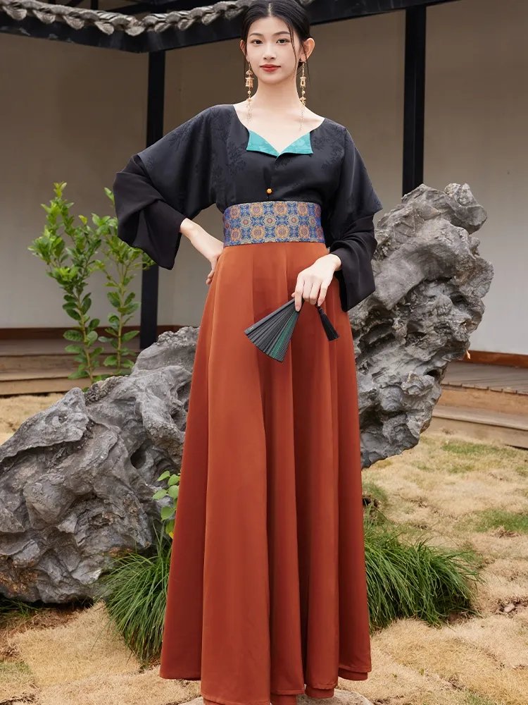 Model wearing a tang-style hanfu dress with a teal collar, brocade belt, and rust-orange 14-panel skirt
