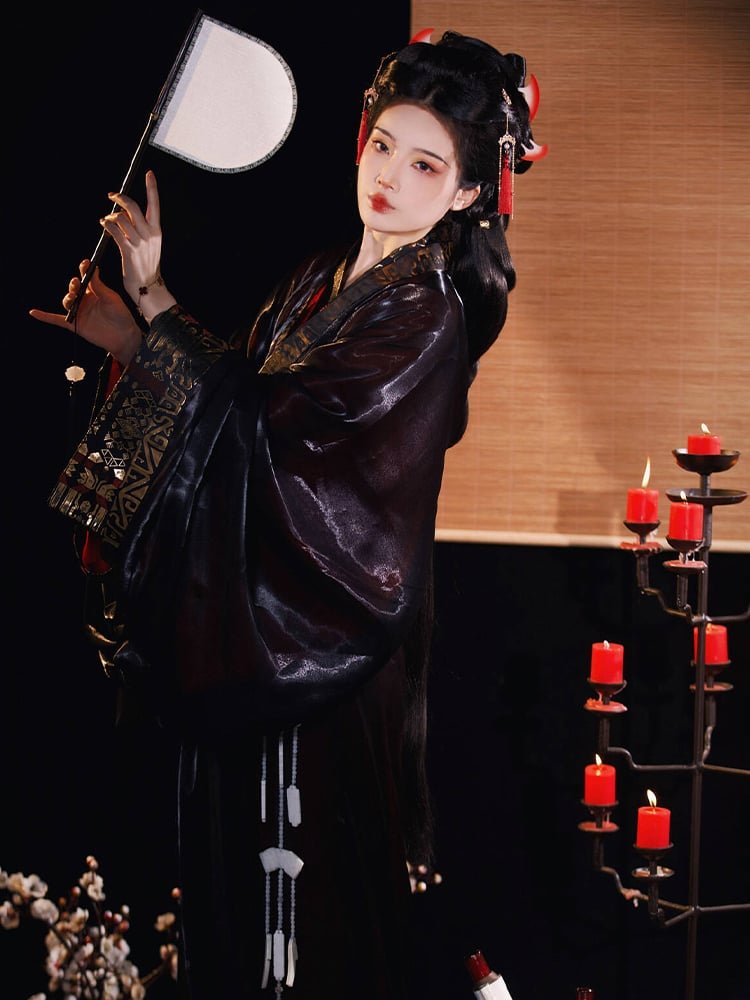 Model in full-length black Hanfu Zhiju with gold trim, holding sword in warrior pose.