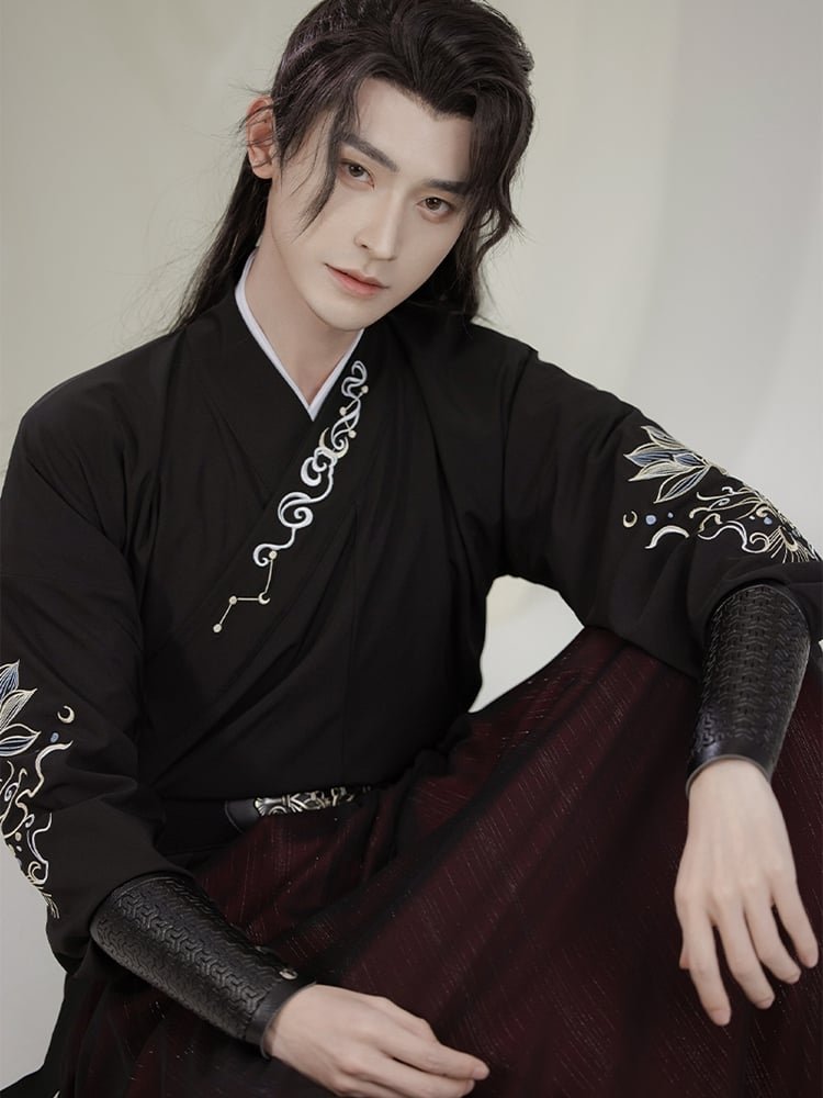 Model wearing black Wuxia Hanfu robe for men with embroidered sleeves, elegant martial arts style.