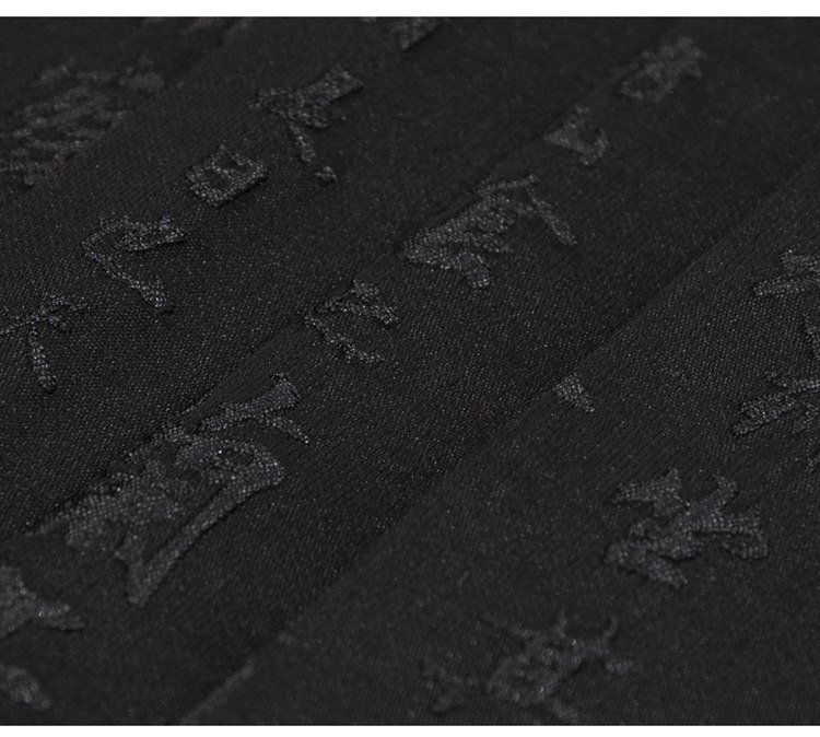 Macro close-up showing the black-on-black jacquard calligraphy pattern inspired by Lantingji Xu on the Hanfu skirt.