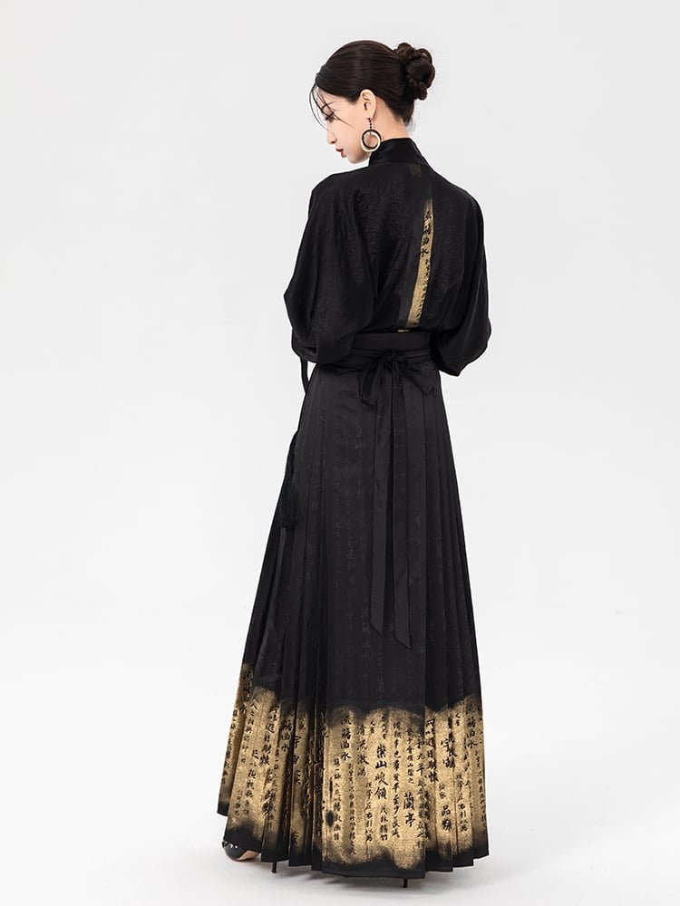 Rear view of the embroidered gold MAMIAN skirt showing subtle jacquard calligraphy patterns woven into the black fabric.