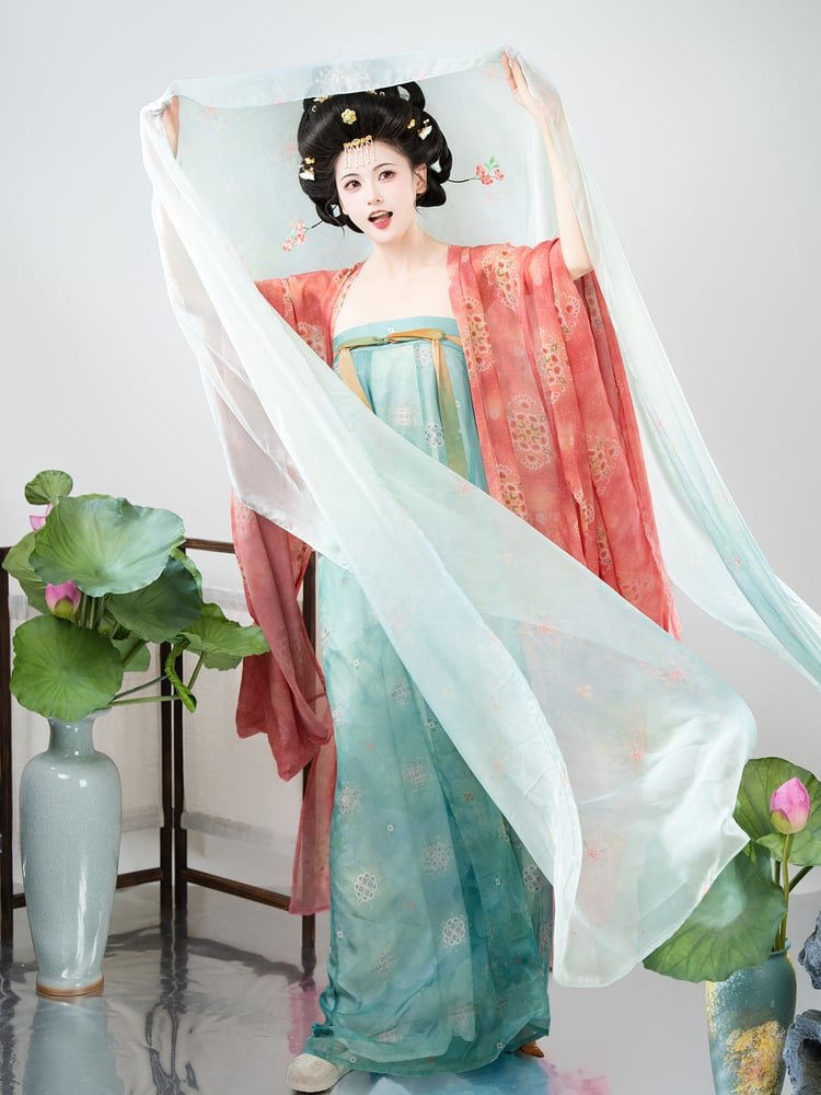 Model raising her arms while the peach-red shawl and white chiffon drape flow elegantly in the air.