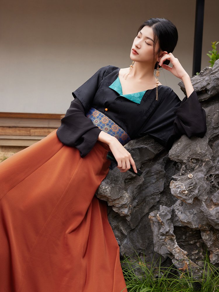 Model sitting while wearing tang-style hanfu dress with teal collar and wide sleeves